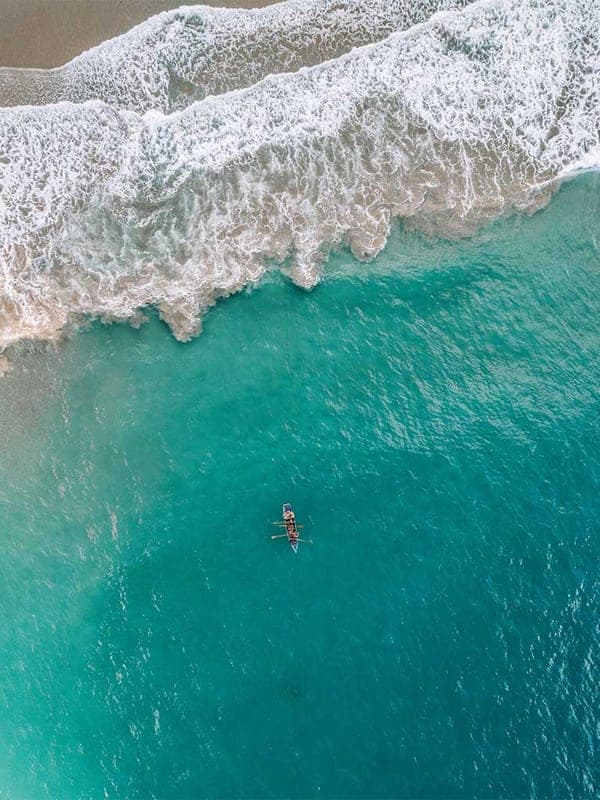 Top-down aerial of a lone fishing boat on the turquoise water off Playa El Valle